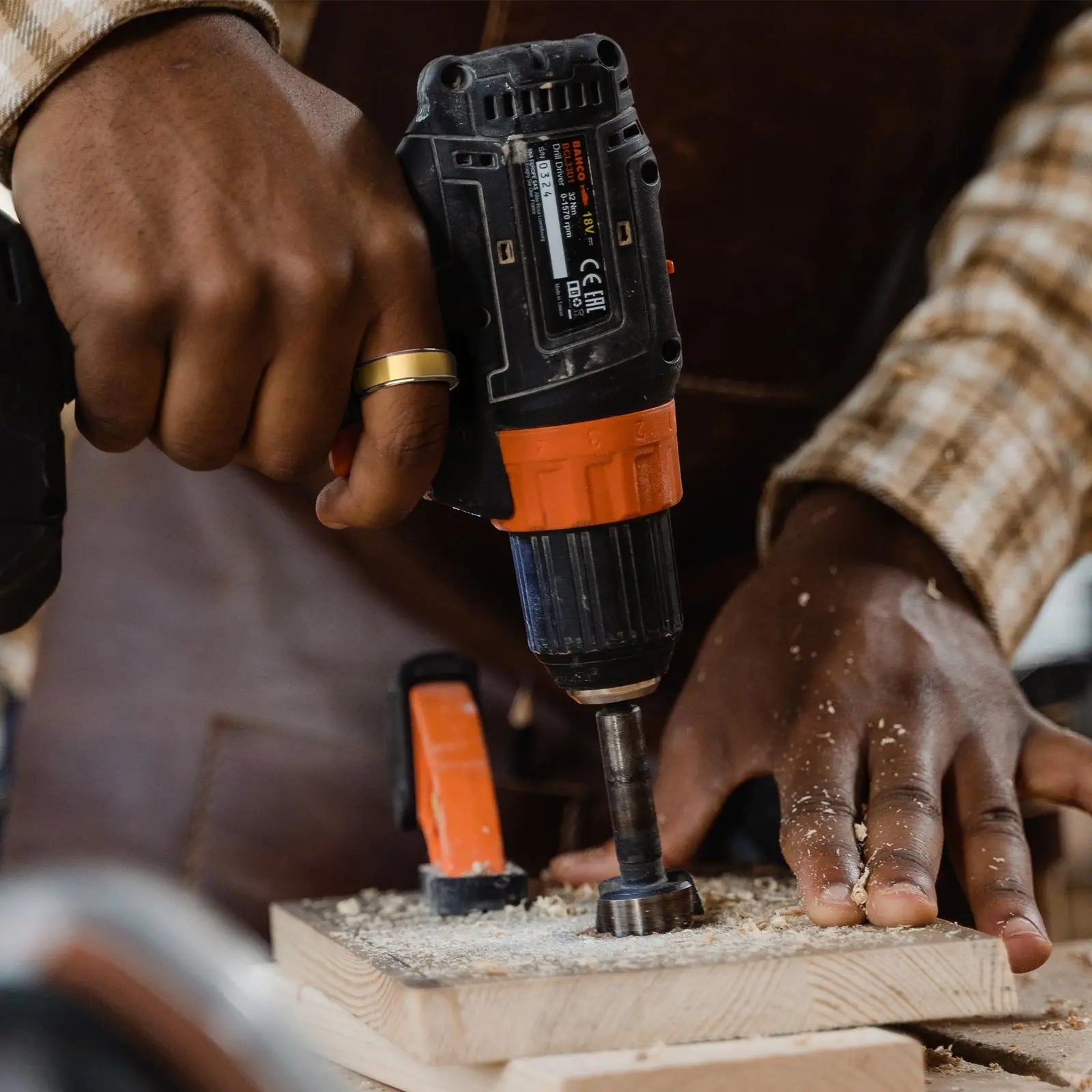 Gold smart ring on finger during woodworking, paired with power drill for sleep tracking and health monitoring.