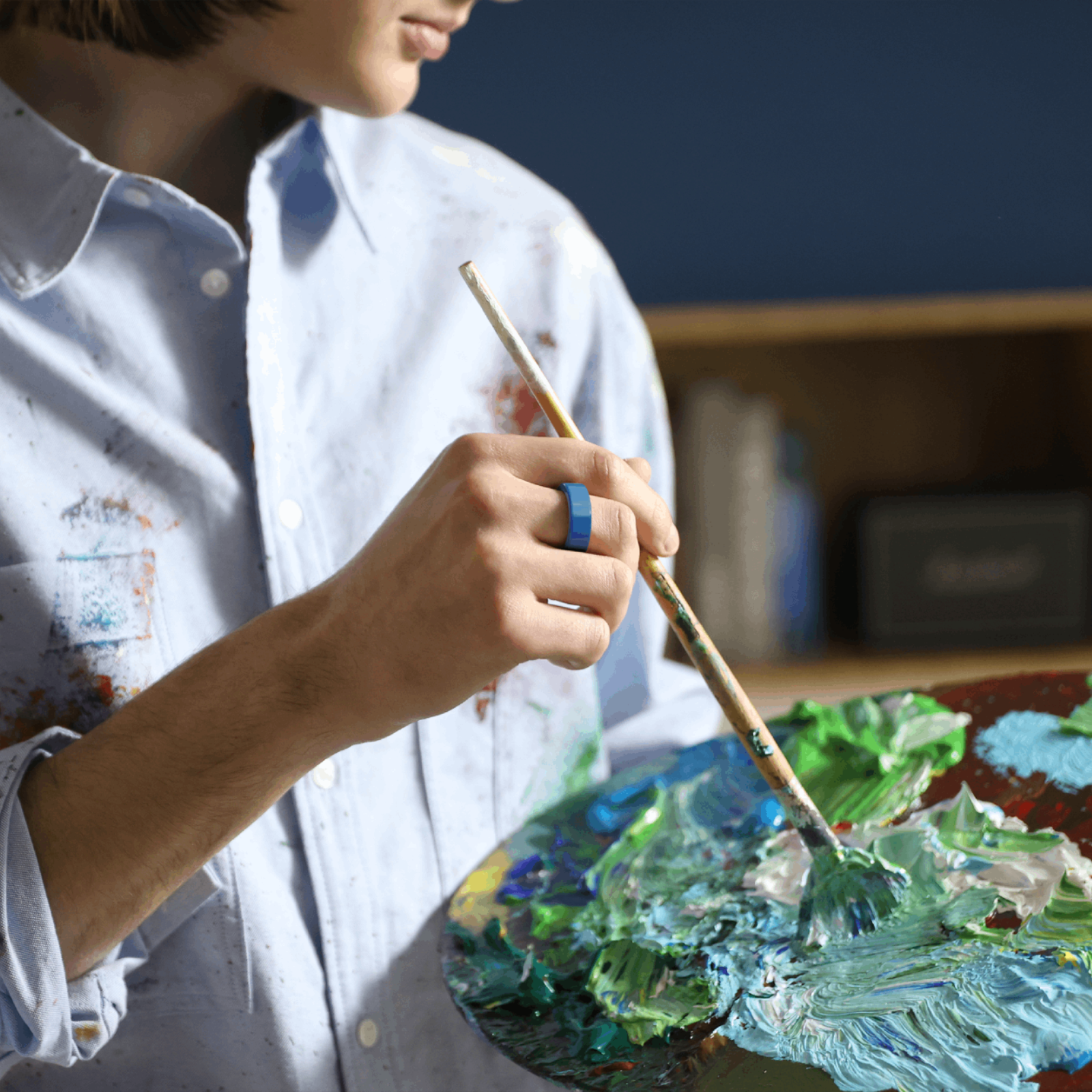 Blue silicone ring protector on artist's hand. Ideal for sleep and health monitoring. Lightweight and hypoallergenic.