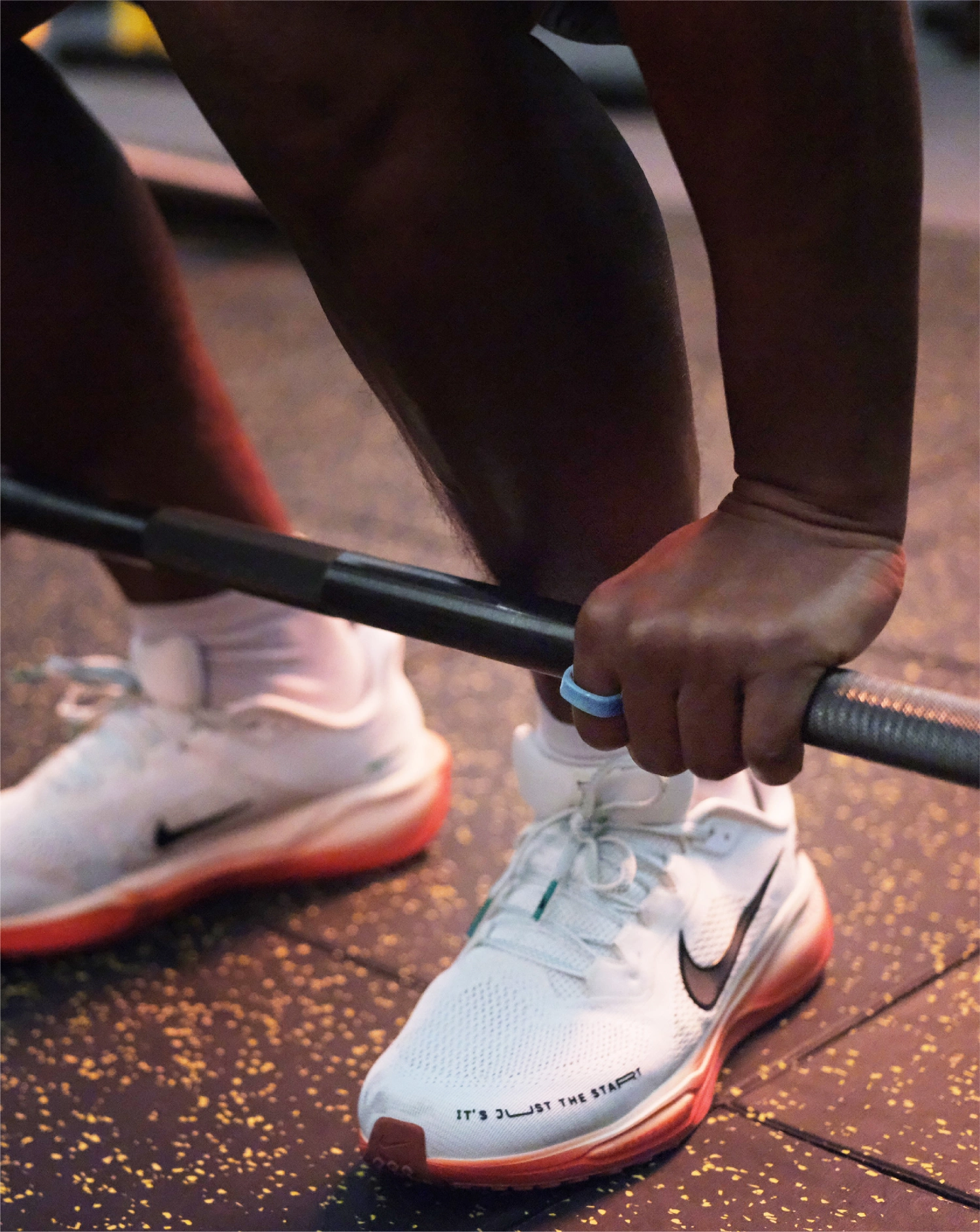 Athlete lifting barbell with light blue smart ring, emphasizing fitness tracking.