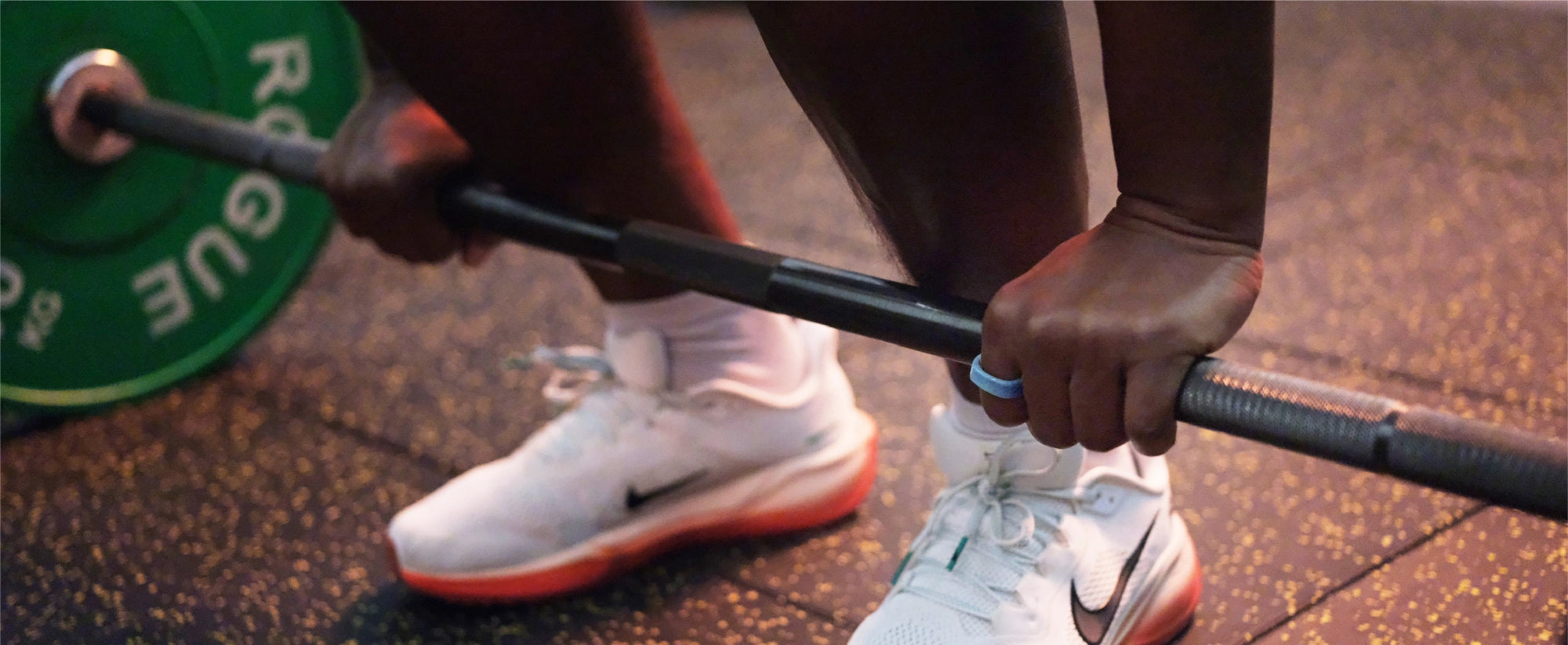 Athlete lifting barbell wearing light blue smart ring, emphasizing health and fitness tracking.