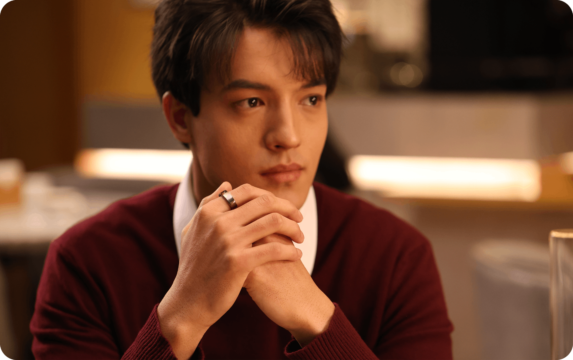 Man wearing a silver health tracking ring, hands clasped, modern tech accessory