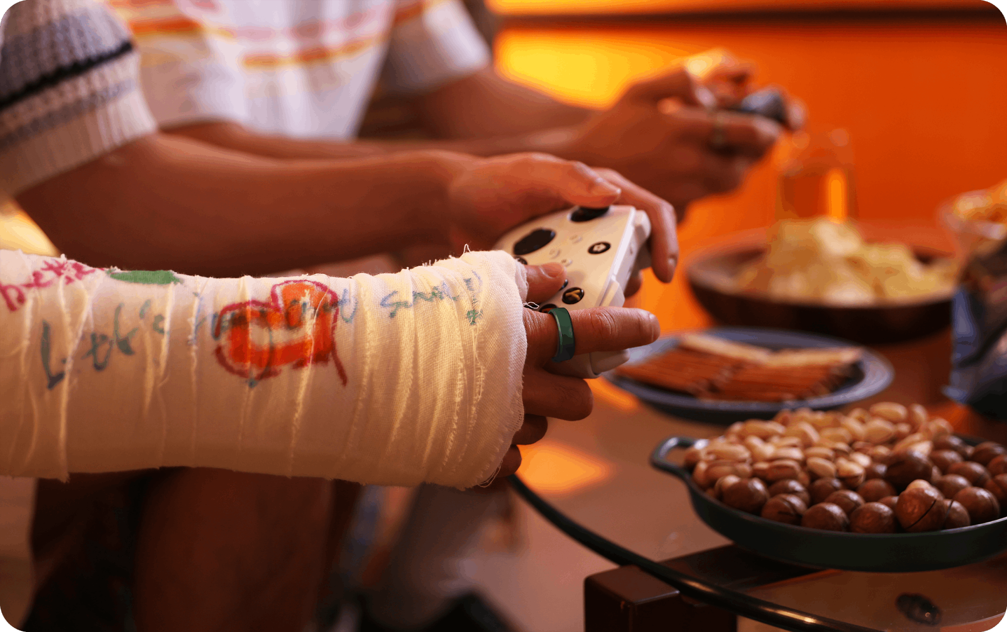 Person with a green smart ring playing a video game, cast with drawings and message on the arm