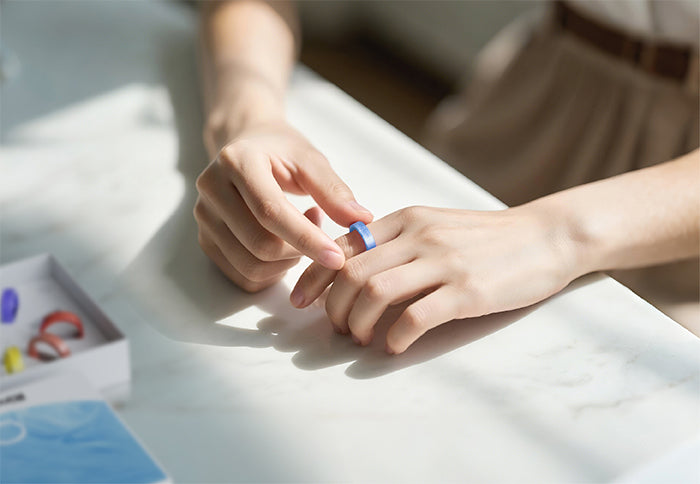 Blue smart ring on a finger, showcasing the design and fit.